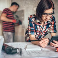 Woman,Using,Smart,Phone,On,The,Table,While,Her,Husband